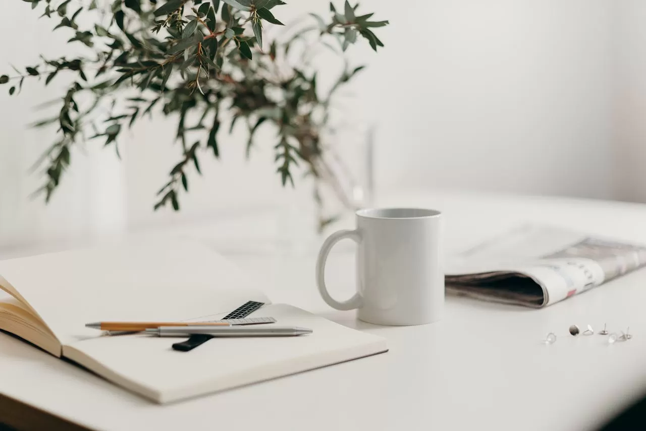 a notebook, newspaper and coffee mug on a table for a life reset