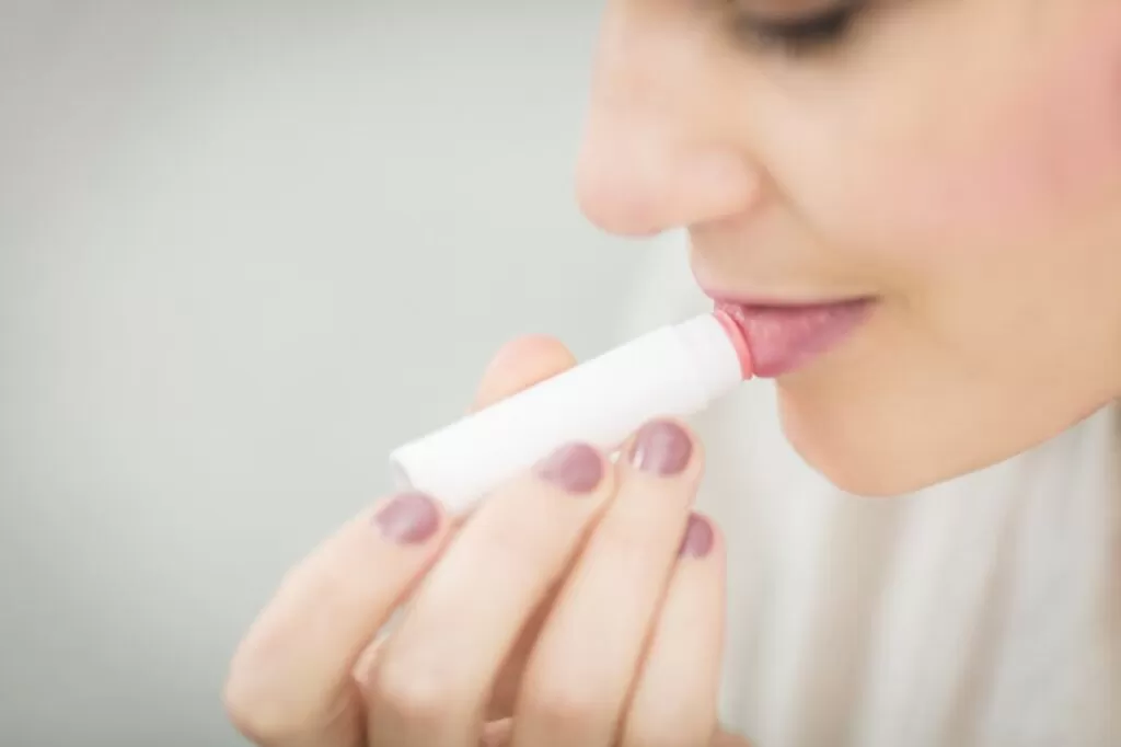 a woman putting lip balm